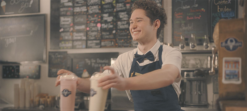 Man serving milkshakes at counter